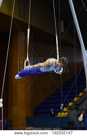 Male Gymnast Performing On Stationary Gymnastic Rings