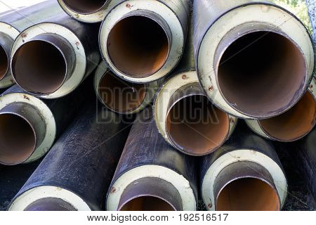 close up shot of a pile stack of big metal pipes tubes with heater isolation insulation and pvc shell at construction site
