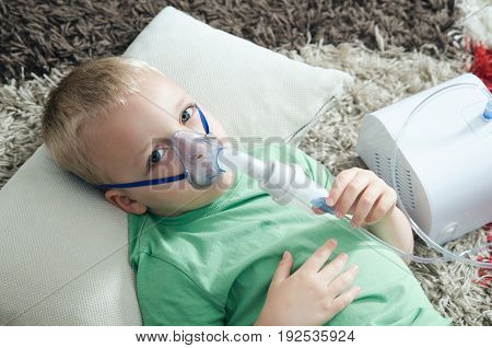 Boy making inhalation with nebulizer at home. child asthma inhaler inhalation nebulizer steam sick cough concept