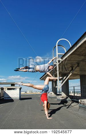 A loving couple of roofer on the roof. The guy and the girl are doing acrobatic stunts. Romance and courage. An unusual date.