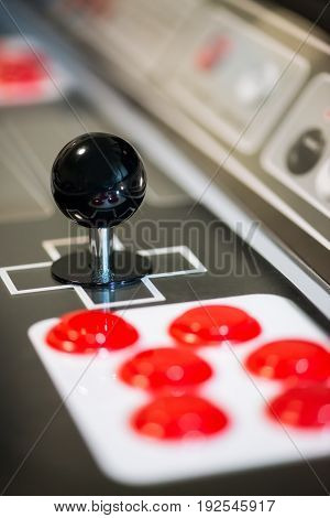 Detail of a black joystick and red buttons on an arcade game machine