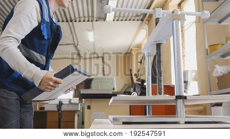 Worker of printing with a stack of paper at the machine, in a printing factory
