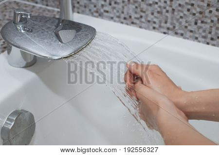 Washing of hands with soap under running water.