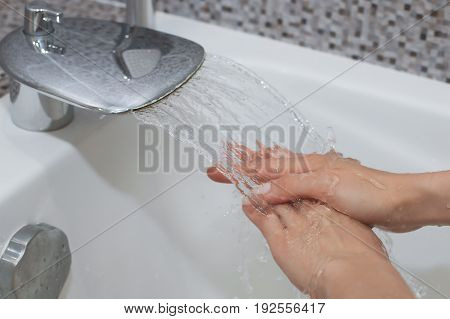 Washing of hands with soap under running water.