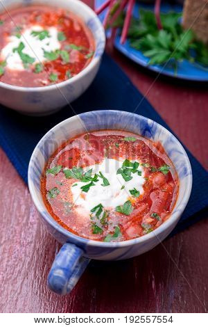 Ukrainian Traditional Borsch. Russian Vegetarian Red Soup  In Blue Bowl On Red Wooden Background.  B