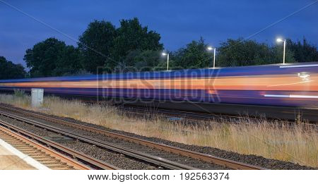 Speeding train through a UK station at night