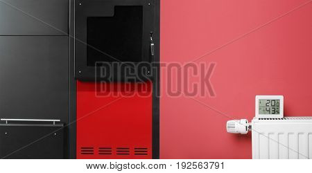 Energy savings concept. Solid fuel boiler and radiator with electronic thermometer on color background