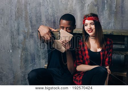 Interracial student couple taking selfie on phone. Black guy and white girl are studying together. Classmates have fun