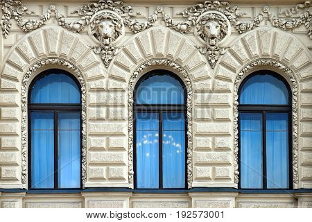 Three blue windows with sculptures of lions in the old building in St. Petersburg
