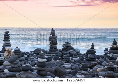 Stack of pebbles on a big rock at the beach during the sunset