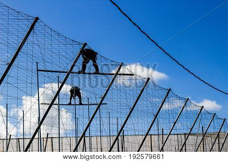 Suspended workers fixing the web in a sunny and cloudy day