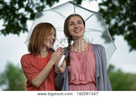 Two women walking park in rain and talk. Friendship and people communication. Rainy day in summer