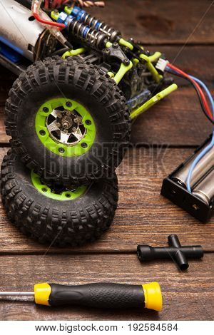 Dismantled broken Rc radio control car crawler model toy repair. Green toy suv in repairshop workplace, closeup