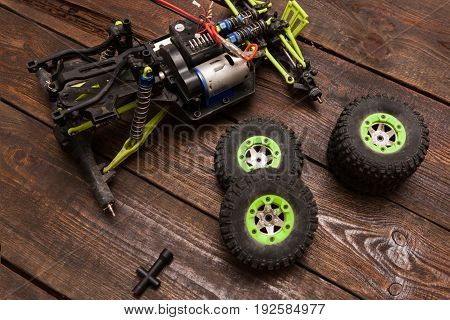 Dismantled broken Rc radio control car crawler model toy repair. Green toy suv in repairshop workplace, top view. Wheels on foreground
