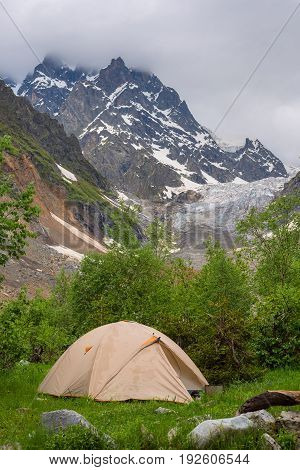 Tent Of Travelers Next To A Glacier In A Mountain Gorge