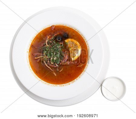 Delicious meat soup with herbs and sour cream. Isolated on a white background.