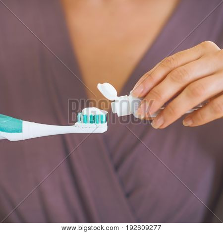 Closeup On Young Woman Squeezing Toothpaste On Toothbrush