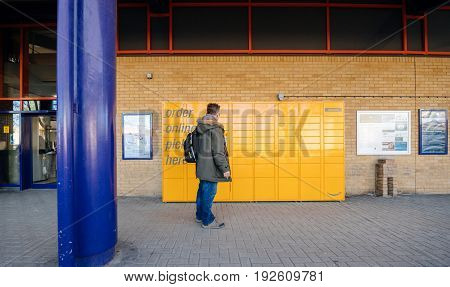 OXFORD UNITED KINGDOM - MAR 2 2017: Man looking at the Amazon locker orange delivery package locker train station - Amazon Locker is a self-service parcel delivery service offered by online retailer Amazon.com. Amazon customers can select any Locker locat