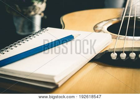 Pencil and Notebook on Acoustic guitar for songwriter