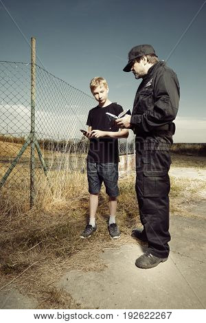 Police man asking teenage boy outdoor in fields