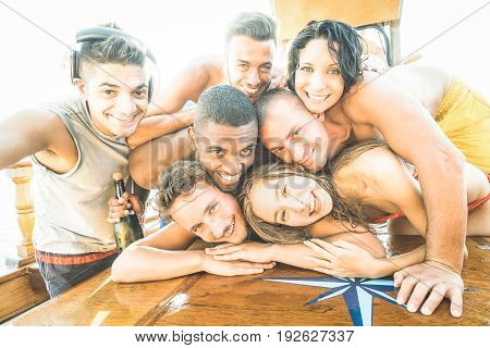 Group of best friends guys and girls taking selfie at sailing boat - Happy youth friendship concept with young multiracial people having fun together at summer beach vacation - Bright backlight filter