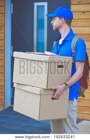 Smiling delivery man in blue uniform delivering parcel box to recipient - courier service concept