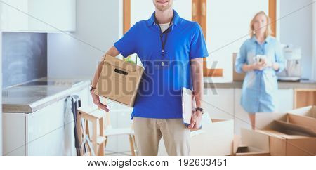 Smiling delivery man in blue uniform delivering parcel box to recipient - courier service concept
