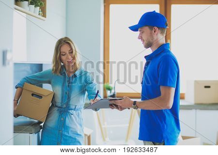 Smiling delivery man in blue uniform delivering parcel box to recipient - courier service concept