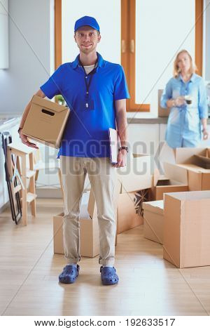 Smiling delivery man in blue uniform delivering parcel box to recipient - courier service concept