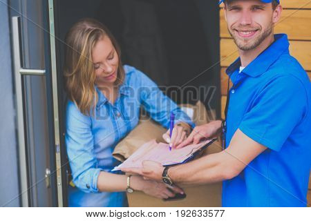 Smiling delivery man in blue uniform delivering parcel box to recipient - courier service concept