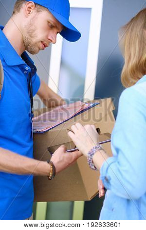 Smiling delivery man in blue uniform delivering parcel box to recipient - courier service concept