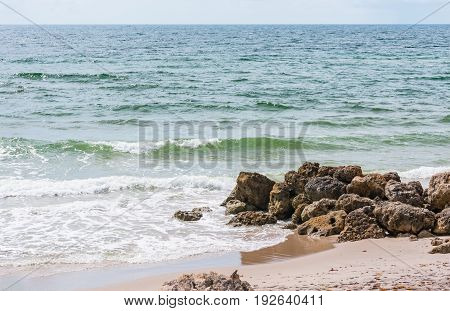 waves crashing on beach shore rocks on a hot summer day in South Florida