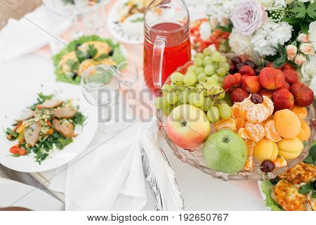 fresh ftuit on holiday table. Wine glasses with napkins, glasses and salads.