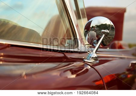 Classic retro vintage red car. Car mirror. The car is older than 1985.