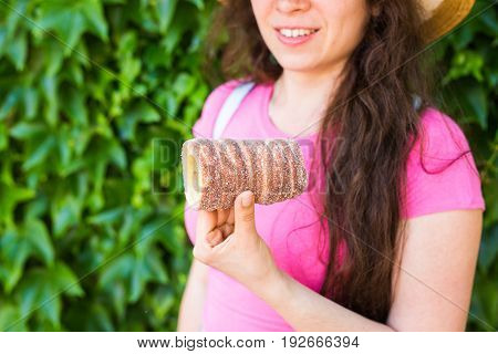 Close-up of young female tourist with traditional czech dessert trdelnik in Prague. Czech Republic. Outdoor.