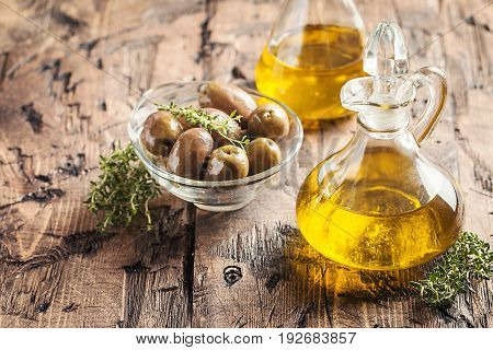 olive oil in glass bottle and olives over old wooden table
