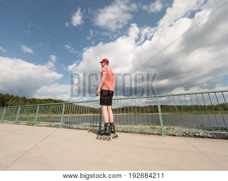 Roller Skater In Action. Man Ride In Inline Skates Ride Along Promenade Handrail, Sky In Background