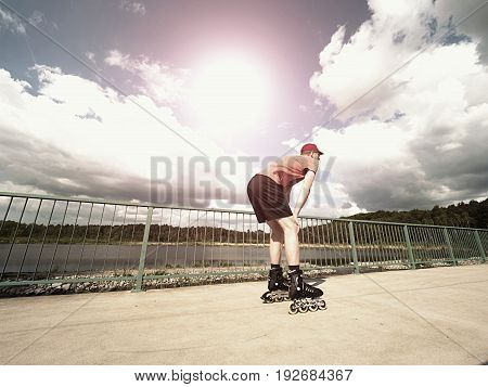 Roller Skater In Action. Man Ride In Inline Skates Ride Along Promenade Handrail, Sky In Background