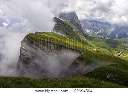 Odle mountain range covered by clouds. Gardena Valley in sunlit. Seceda peak view. Puez-Odle National Park Dolomites Italy