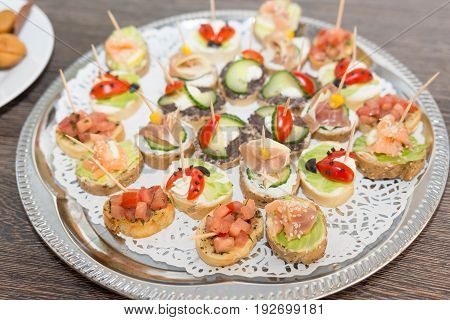 Delicious little sandwiches bites with bacon cherry tomato olives cucmber lettuce corn on a tray