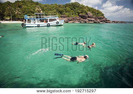 PHU QUOC, VIETNAM - March 22, 2017: Snorkeling divers near a remote tropical island with palm trees and blue ocean near Phu Quoc, Vietnam