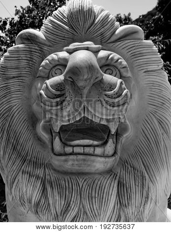 Stone calving of lions head and face with its mane in black and white.