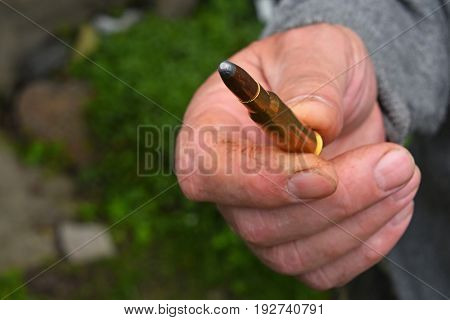 Old man hand holding and showing one 7.62 mm caliber ammunition bullet