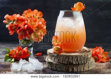 Floral pastel peach and pink brunch cocktail garnished with quince flowers over old rustic background.