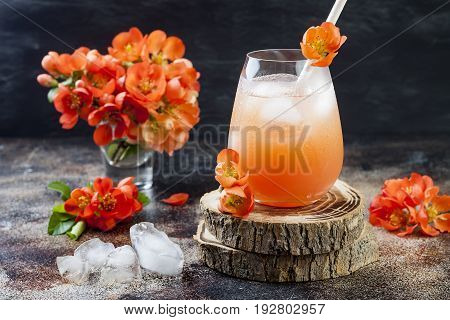 Floral pastel peach and pink brunch cocktail garnished with quince flowers over old rustic background.