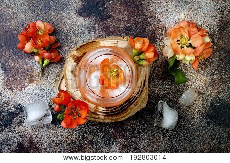 Floral pastel peach and pink brunch cocktail garnished with quince flowers over old rustic background. Top view flat lay copy space