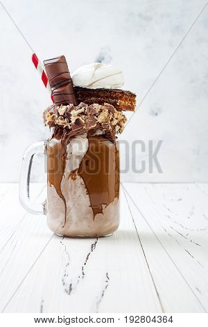 Chocolate indulgent exreme milkshake with brownie cake marshmallow and sweets. Crazy freakshake food trend. Copy space