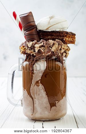Chocolate indulgent exreme milkshake with brownie cake marshmallow and sweets. Crazy freakshake food trend.