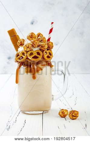 Salted caramel indulgent exreme milkshakes with brezel waffles popcorn and whipped cream. Crazy freakshake food trend. Copy space