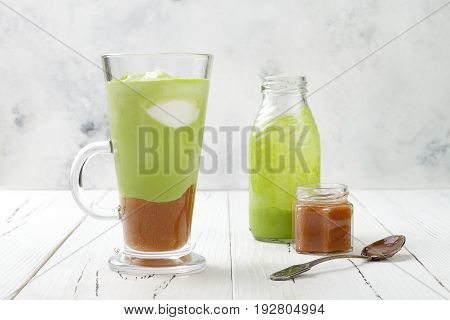 Matcha latte with salted caramel in tall glass.